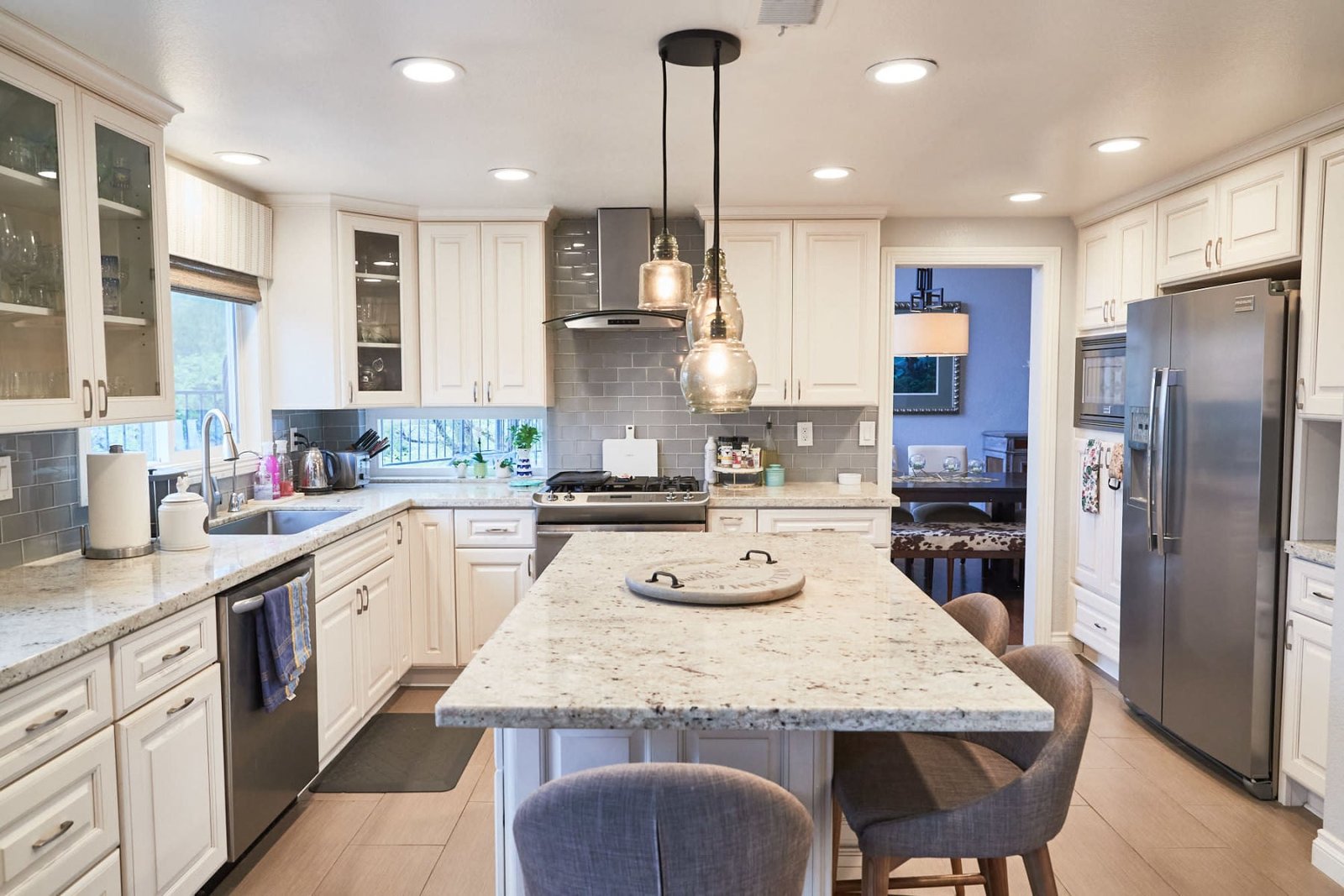 Updated kitchen with white cabinets, granite island, and stainless appliances