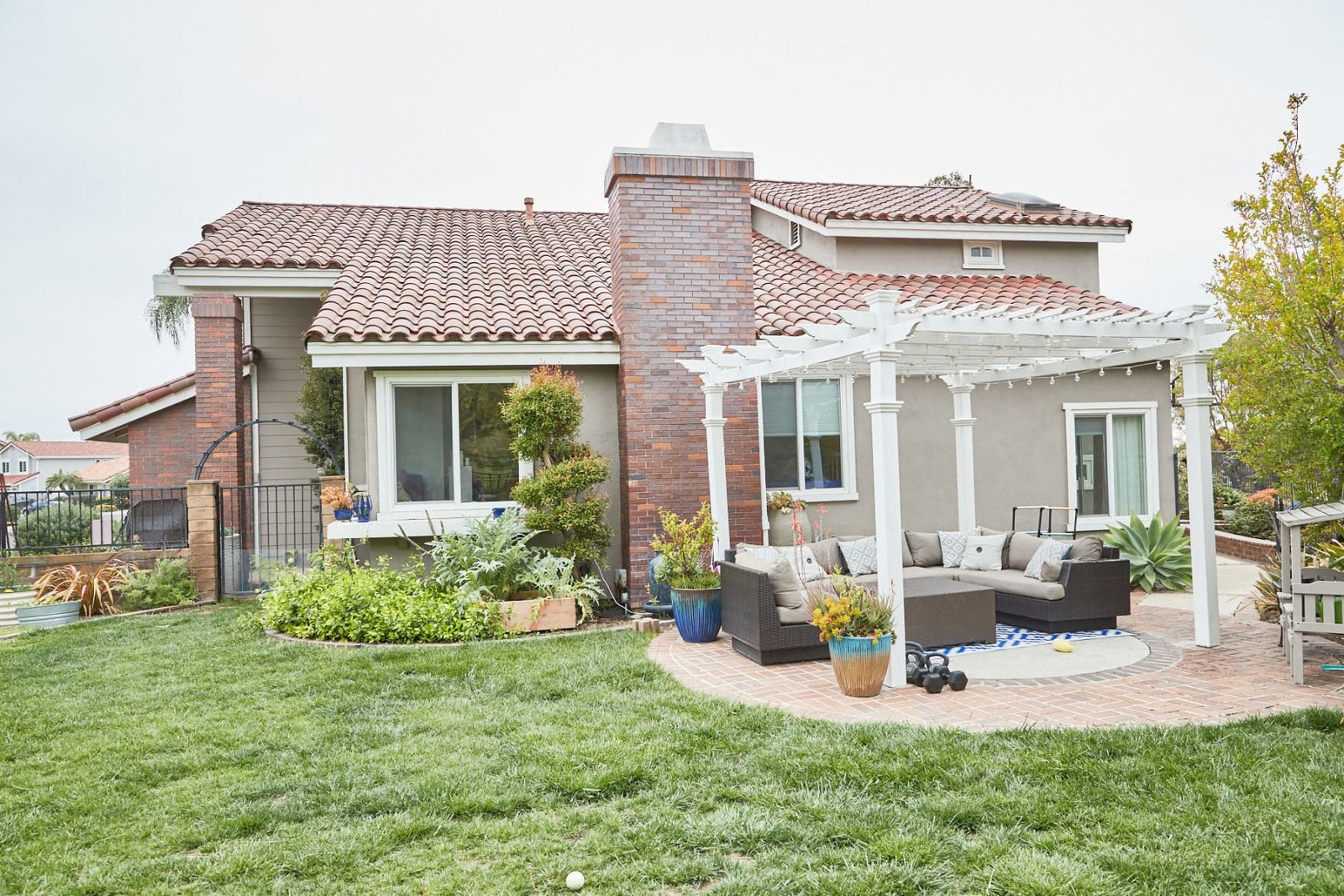 Backyard lawn and pergola behind a two-story family home